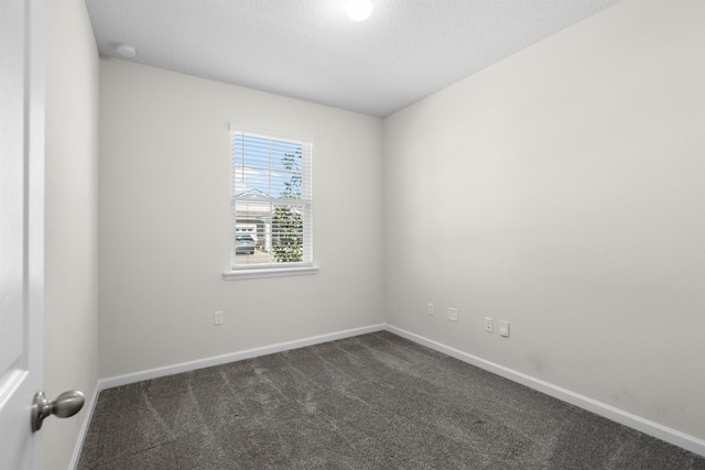 638 Honeycomb Trl, Saint Augustine, FL 32095 - spare room with baseboards, dark carpet, and a textured ceiling
