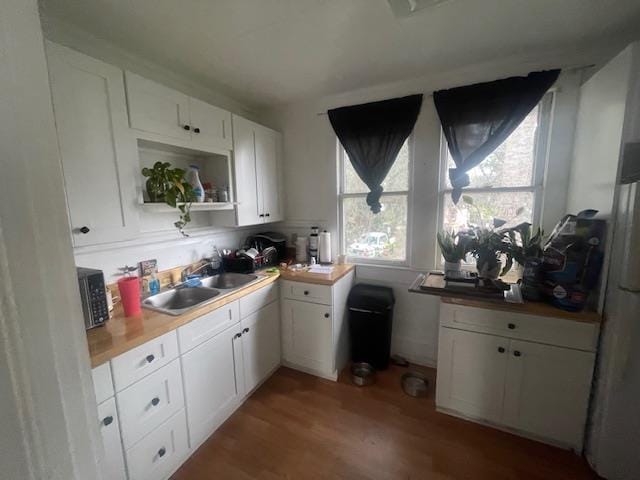 kitchen featuring wood-type flooring, white cabinetry, and sink