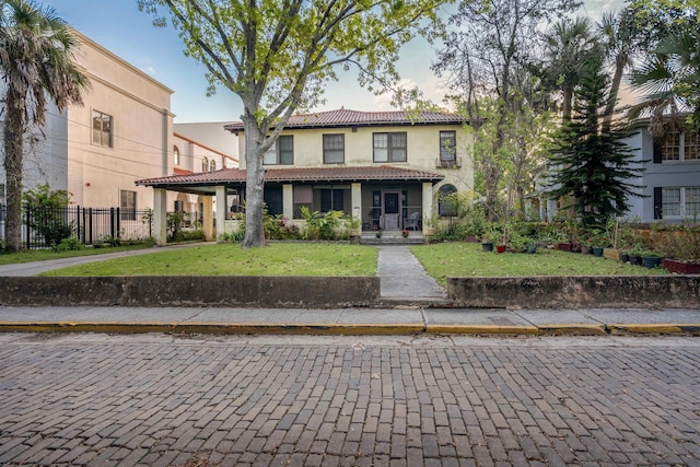 mediterranean / spanish-style home featuring covered porch and a front yard