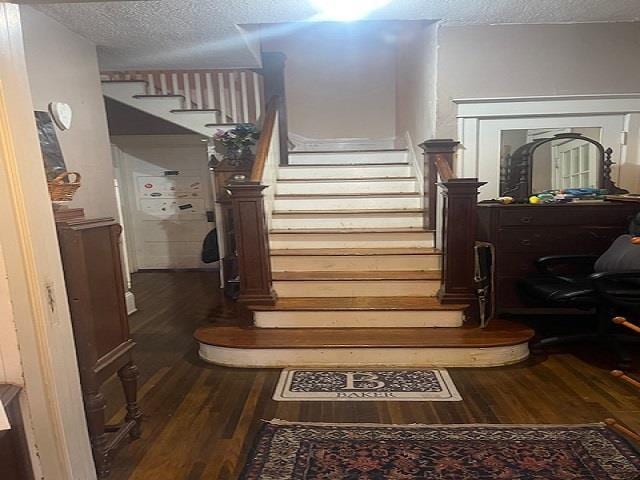 staircase featuring wood-type flooring and a textured ceiling