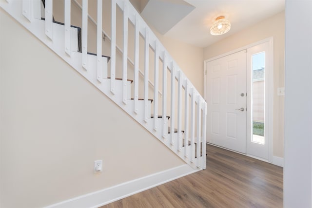 foyer entrance with baseboards, wood finished floors, and stairs