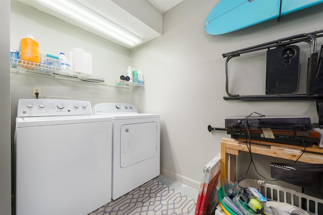 clothes washing area featuring baseboards, laundry area, and washer and clothes dryer