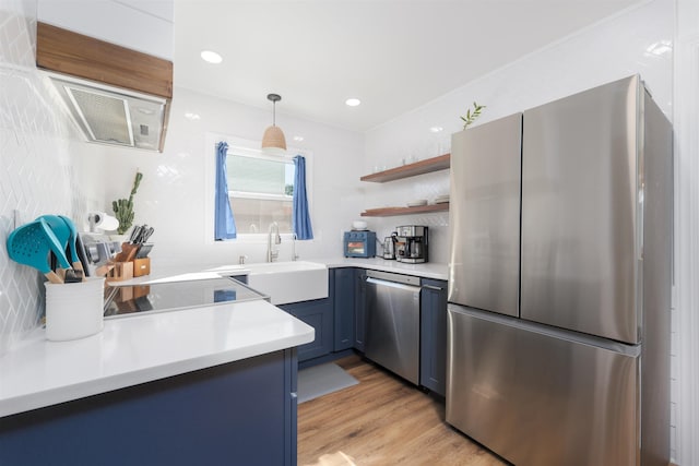 kitchen featuring a sink, open shelves, light wood-style floors, appliances with stainless steel finishes, and light countertops