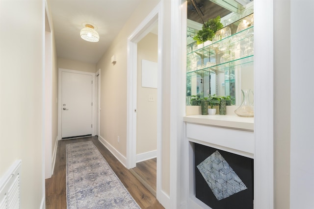 hallway featuring dark wood finished floors and baseboards