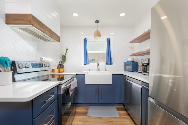 kitchen featuring custom range hood, a sink, open shelves, blue cabinetry, and appliances with stainless steel finishes