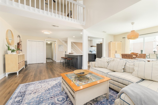 living area with stairs, wood finished floors, visible vents, and baseboards