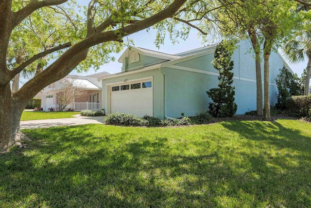 view of side of property with a garage, a lawn, concrete driveway, and stucco siding