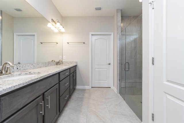 bathroom with a shower with door, vanity, and tile patterned flooring