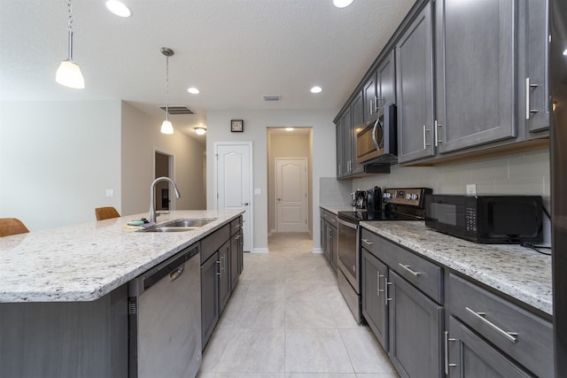 kitchen with sink, pendant lighting, a breakfast bar area, a kitchen island with sink, and appliances with stainless steel finishes