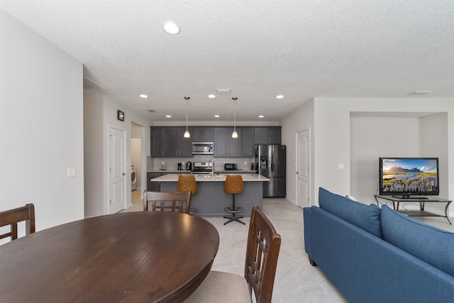 dining space featuring sink, a textured ceiling, and washer / dryer