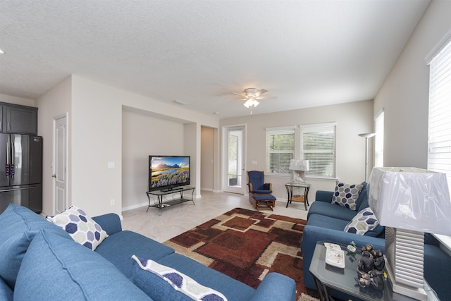 living room featuring a wealth of natural light, ceiling fan, and a textured ceiling