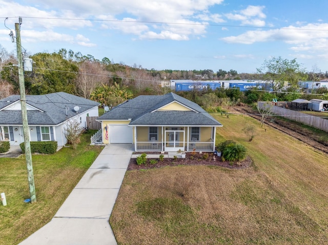 single story home featuring a porch, a front yard, and a garage