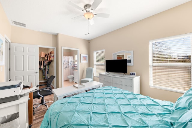 bedroom featuring a spacious closet, connected bathroom, ceiling fan, a closet, and multiple windows