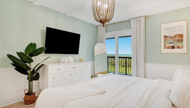 bedroom with access to outside, wood finished floors, and an inviting chandelier