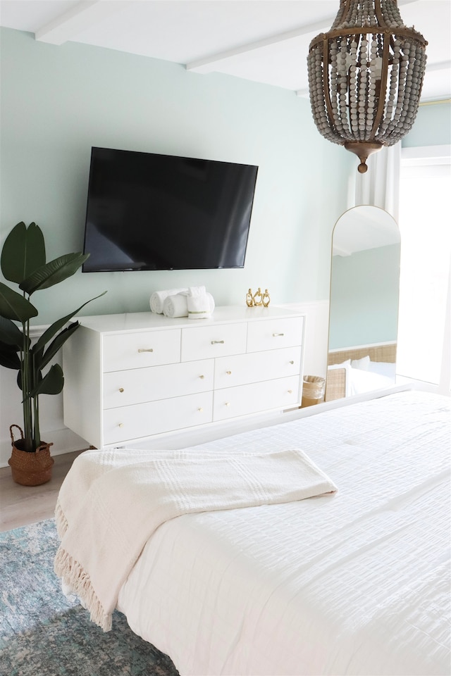 bedroom featuring beamed ceiling and wood finished floors