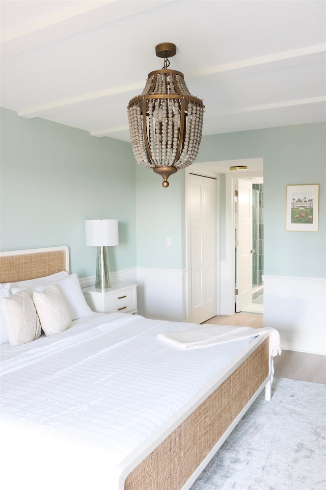 bedroom featuring beam ceiling and wood finished floors