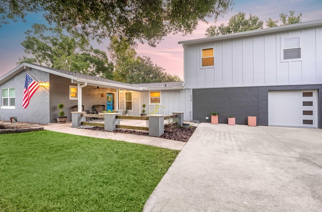 back house at dusk with a garage and a lawn