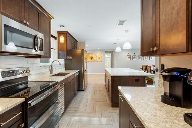 214 Deltona Blvd, Saint Augustine, FL 32086 - kitchen featuring stainless steel appliances, dark brown cabinetry, tasteful backsplash, hanging light fixtures, and a kitchen island