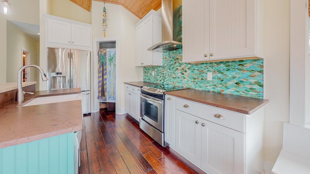 kitchen featuring appliances with stainless steel finishes, wall chimney exhaust hood, white cabinetry, sink, and vaulted ceiling