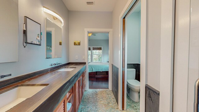 bathroom with vanity, toilet, and tile walls