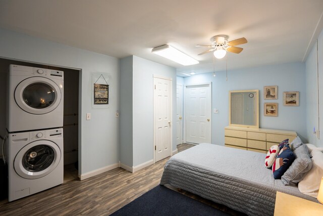 bedroom featuring stacked washer and clothes dryer, dark wood-type flooring, and ceiling fan