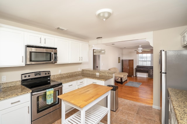 kitchen featuring white cabinetry, ceiling fan, hanging light fixtures, appliances with stainless steel finishes, and light wood-type flooring