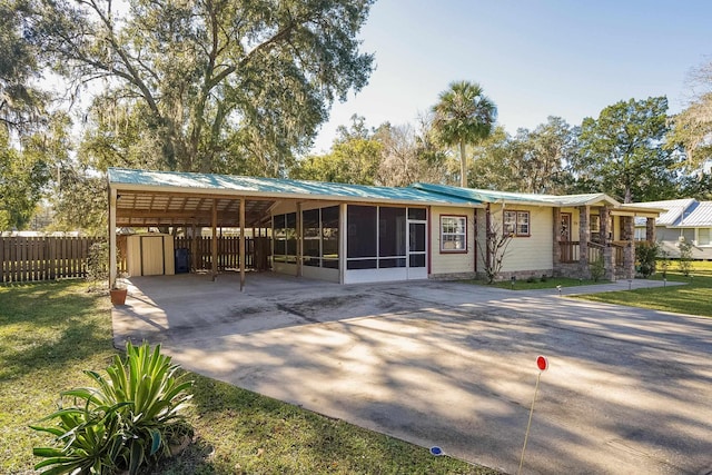 view of front of property featuring a sunroom, a front lawn, and a carport