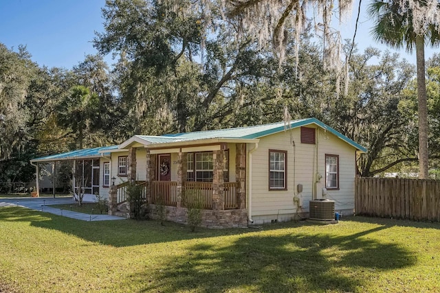 rear view of property featuring a yard, cooling unit, and covered porch