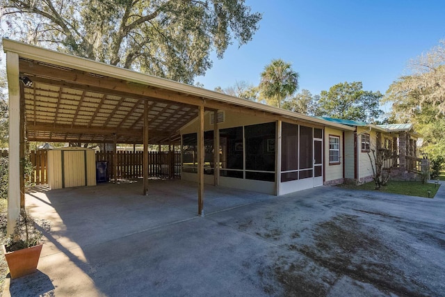 view of front of property featuring a carport, a sunroom, and a shed