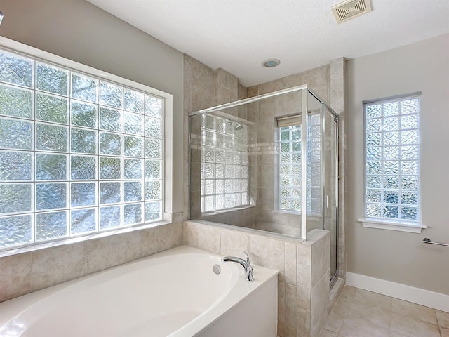 bathroom with tile patterned flooring, separate shower and tub, and a textured ceiling