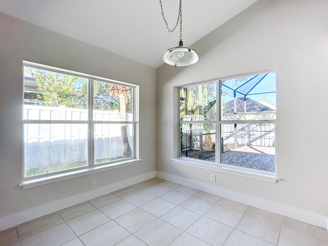 unfurnished dining area with light tile patterned flooring, a healthy amount of sunlight, and vaulted ceiling