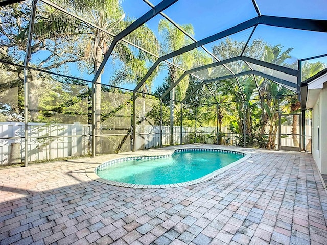 view of pool with glass enclosure and a patio