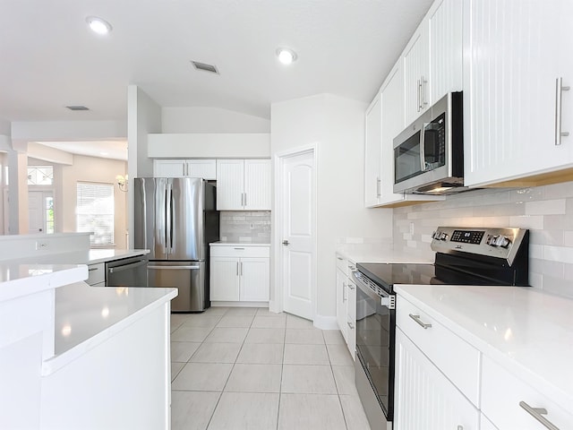 kitchen featuring decorative backsplash, appliances with stainless steel finishes, white cabinetry, and light tile patterned flooring