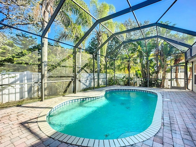 view of pool with glass enclosure and a patio area