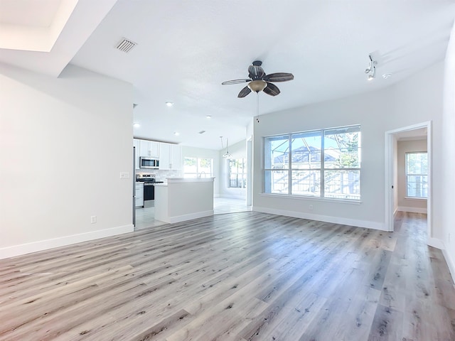 unfurnished living room featuring ceiling fan, a healthy amount of sunlight, and light wood-type flooring