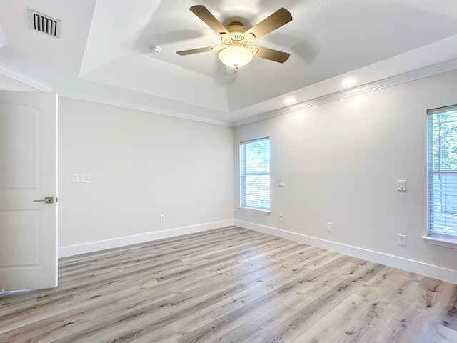 unfurnished room featuring light wood-type flooring, a raised ceiling, ceiling fan, and crown molding