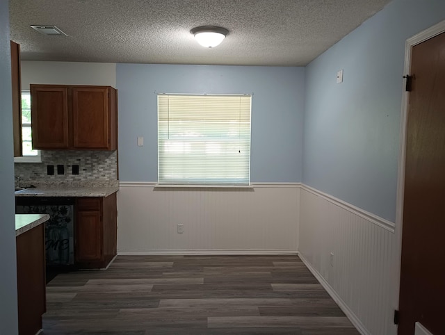 304 Las Olas Rd, Saint Augustine, FL 32084 - kitchen featuring wood finished floors, a wainscoted wall, a textured ceiling, brown cabinets, and light countertops