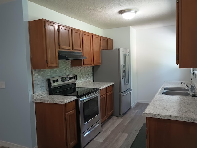 304 Las Olas Rd, Saint Augustine, FL 32084 - kitchen featuring appliances with stainless steel finishes, under cabinet range hood, light wood finished floors, decorative backsplash, and light countertops