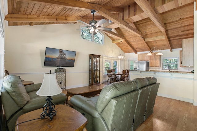 living room featuring high vaulted ceiling, ceiling fan with notable chandelier, beamed ceiling, light hardwood / wood-style floors, and wood ceiling