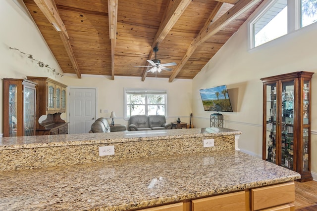 kitchen with light stone countertops, ceiling fan, beam ceiling, high vaulted ceiling, and wooden ceiling