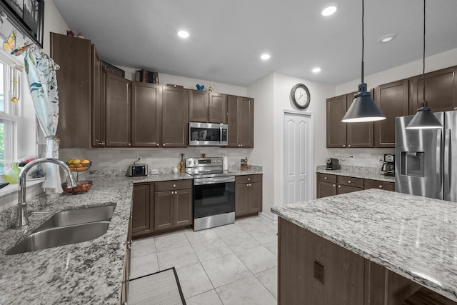 811 Sandstone Dr, Saint Augustine, FL 32086 - kitchen with light stone counters, a sink, stainless steel appliances, dark brown cabinetry, and backsplash