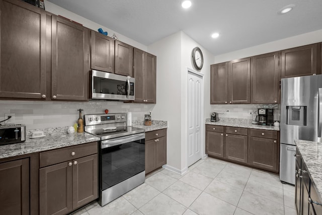 811 Sandstone Dr, Saint Augustine, FL 32086 - kitchen with light stone countertops, dark brown cabinetry, decorative backsplash, light tile patterned flooring, and stainless steel appliances