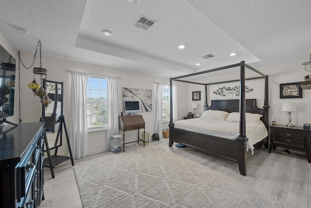 811 Sandstone Dr, Saint Augustine, FL 32086 - bedroom featuring visible vents, a textured ceiling, a tray ceiling, and light wood-style floors