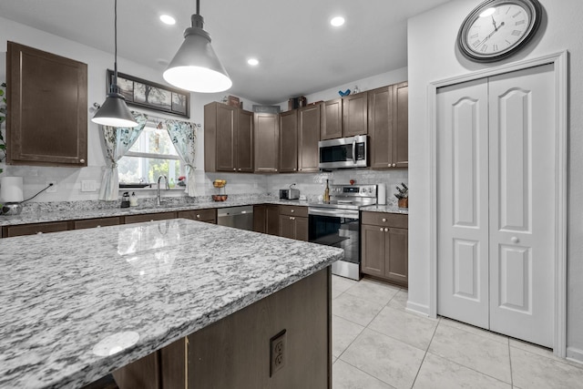 811 Sandstone Dr, Saint Augustine, FL 32086 - kitchen with light stone counters, a sink, stainless steel appliances, dark brown cabinetry, and backsplash