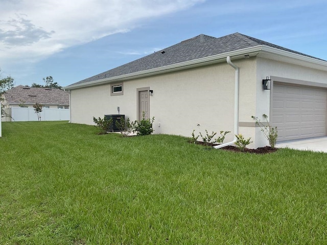 rear view of house featuring cooling unit, a garage, and a yard