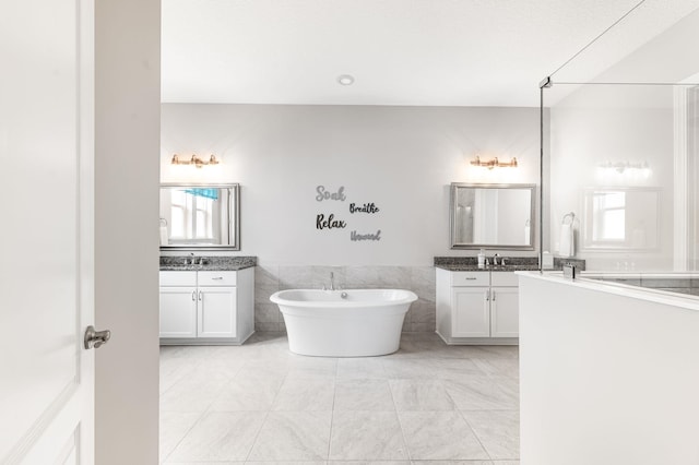 bathroom with vanity, tile patterned floors, a bathtub, and tile walls