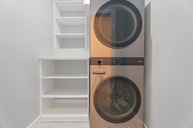 washroom featuring stacked washer / dryer and baseboards