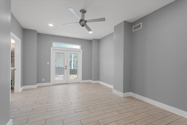 unfurnished room with a ceiling fan, visible vents, baseboards, light wood-style floors, and french doors