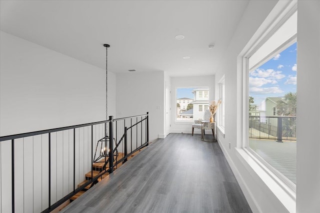 corridor featuring an upstairs landing, dark wood-type flooring, and baseboards