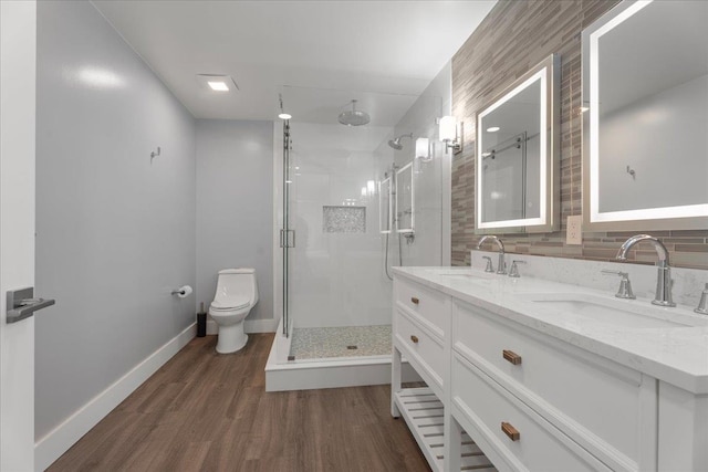 full bathroom featuring toilet, wood finished floors, a stall shower, and a sink